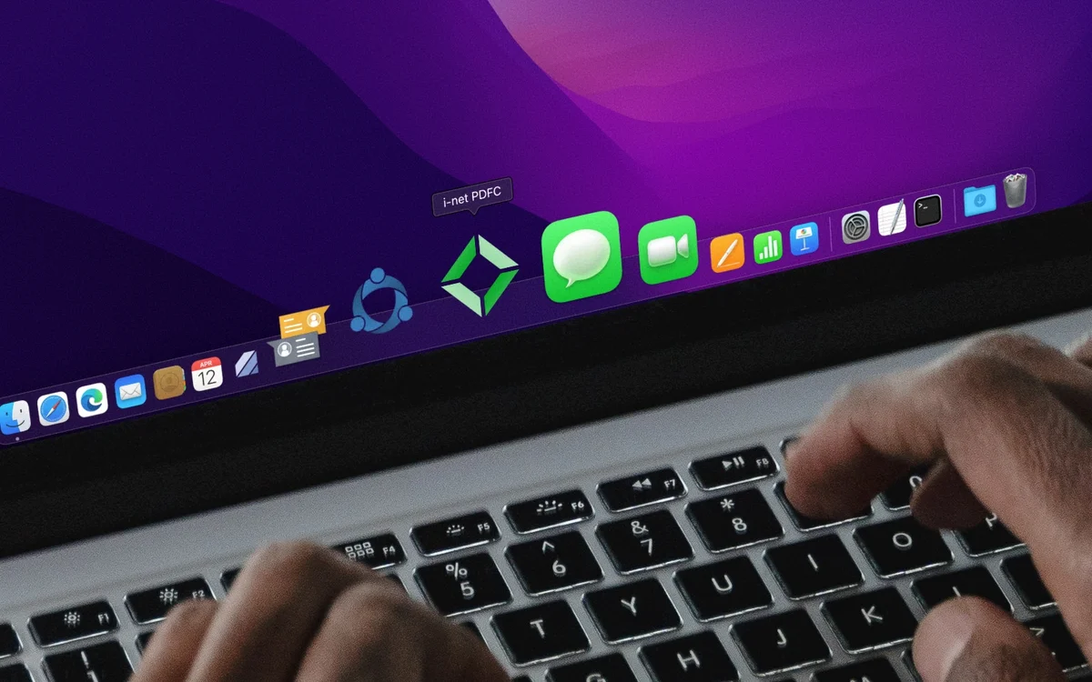 Hände tippen auf einer Laptop-Tastatur, mit Anwendungen im Dock, darunter 'i-net PDFC'.
